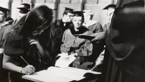 Female student matriculates at Trinity College, signing the matriculation book in Trinity College Chapel