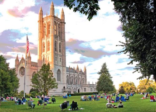 The Trinity College Chapel with students sitting on the grass