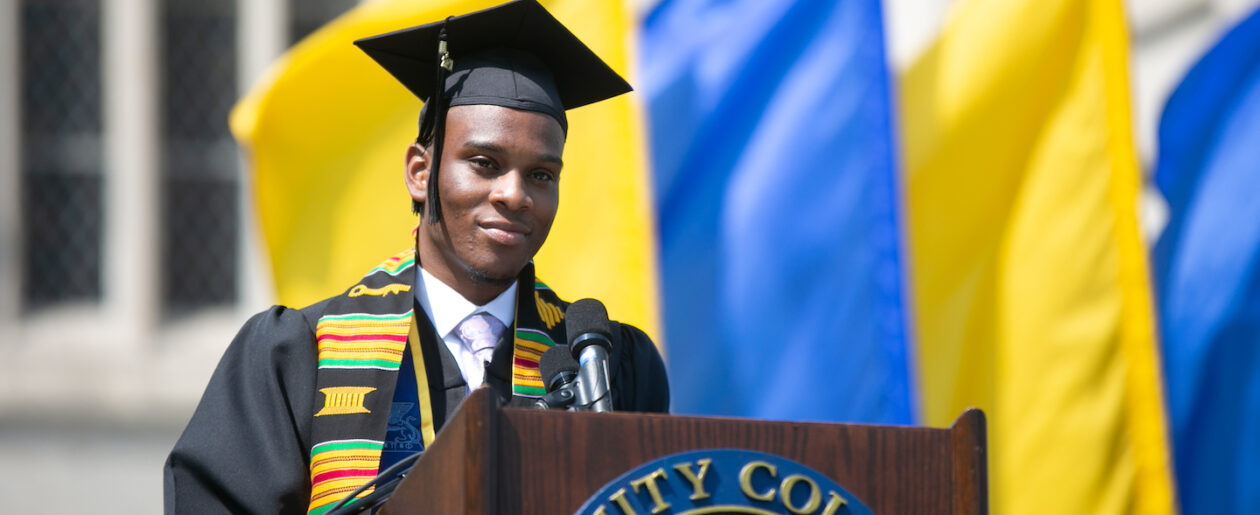 A trinity college grad standing at the graduation podium ready to speak