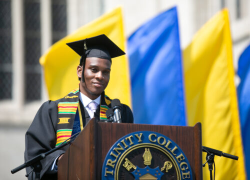 A trinity college grad standing at the graduation podium ready to speak