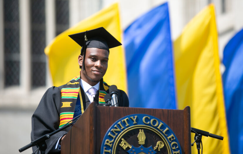 A trinity college grad standing at the graduation podium ready to speak