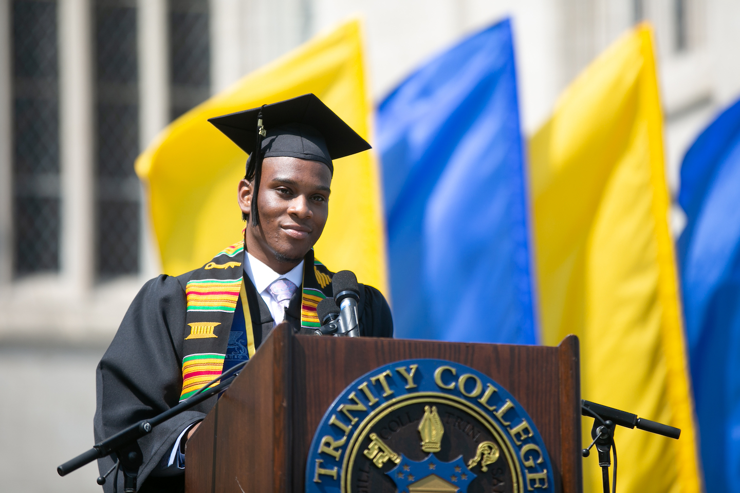 A trinity college grad standing at the graduation podium ready to speak