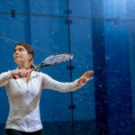 Trinity college squash player serving the ball with racket