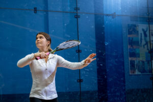 Trinity college squash player serving the ball with racket