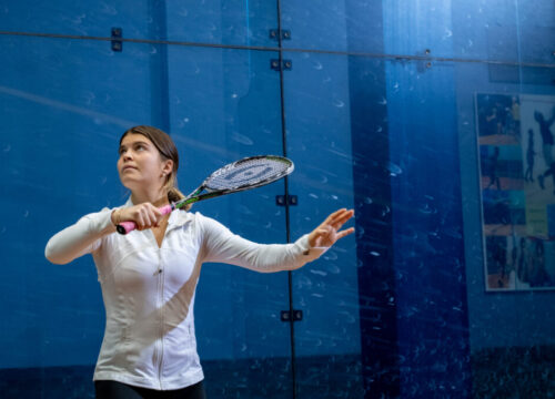 Trinity college squash player serving the ball with racket