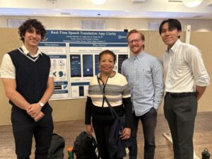 Tadija Ciric, Anthony Smaldore, and Yusuke Abe with President Berger-Sweeney pose in front of a poster