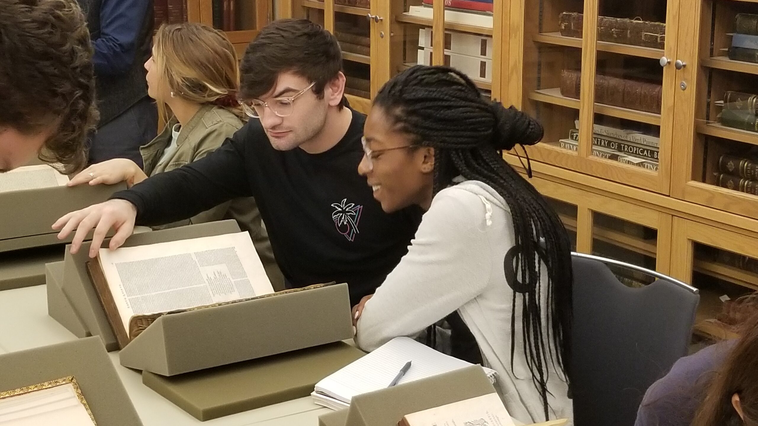 male and female student looking at rare books in Watkinson Library seminar room