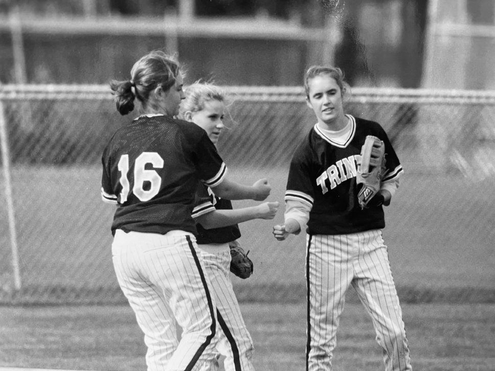 Kate McLaren Sullivan ’99, right, fist-bumps with teammates during a Trinity softball game in the late 1990s.