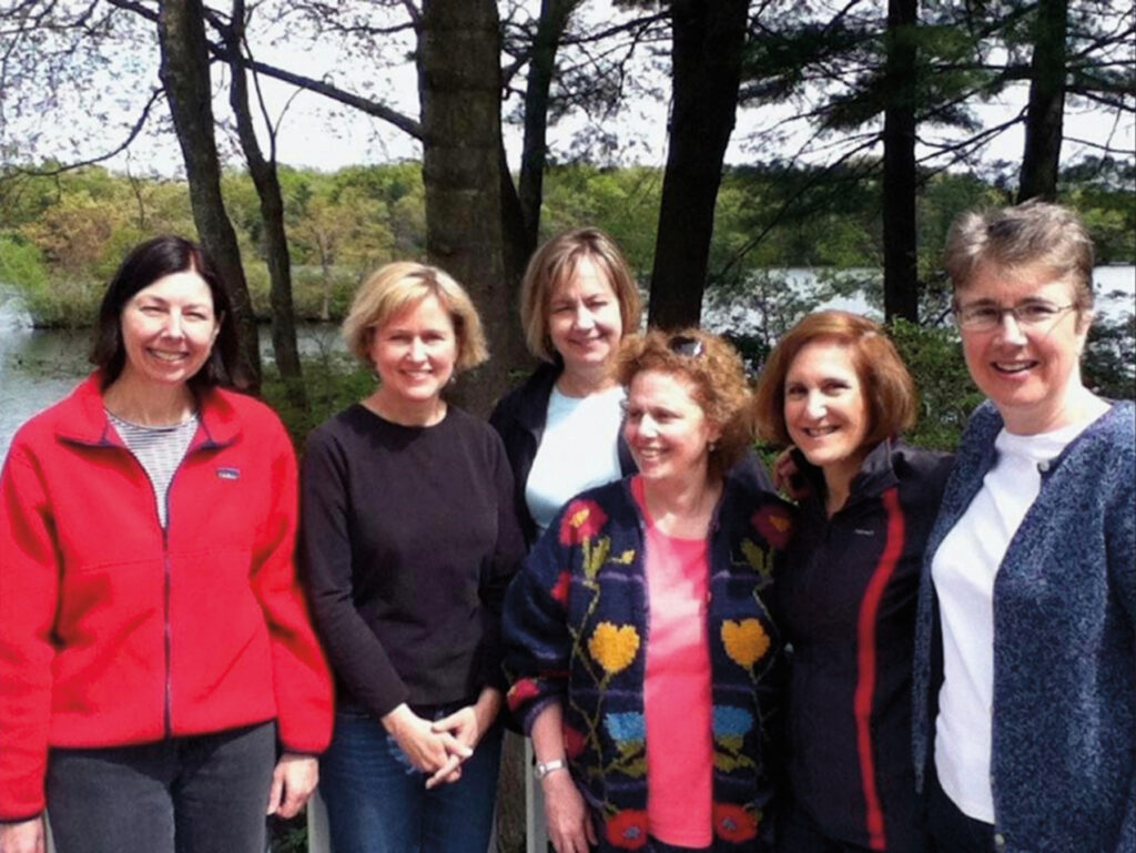 1979 classmates Lynne Bachofner, Jane Terry Abraham, Lynne Bagdis Wilson, Deborah Cushman, Holly Singer, and Sarah Wright Neal outside in front of pine trees