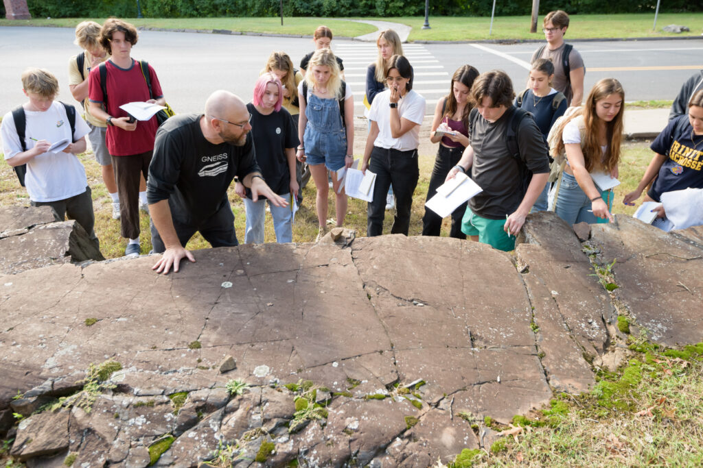 Jonathan Gourley, principal lecturer and laboratory coordinator in the Environmental Science Program, shows his fall 2023 “Introduction to Earth Science” class a rock formation off Summit Street.PHOTO: NICK CAITO