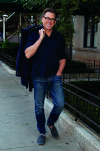 John Howard walking down the street with a jacket casually over his shoulder.