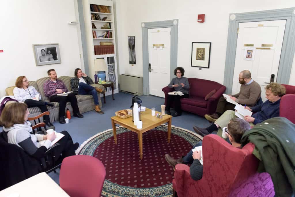 faculty sitting in a room discussing a book