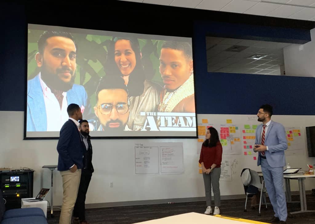 Trinity alumni Tim Flynn ’19 (front left) and Francesca L. Velarde ’19 (second from right) give a presentation during their Infosys training at Trinity’s Liberal Arts Action Lab on Constitution Plaza.