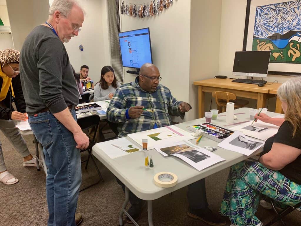 Professor of Fine Arts Joseph Byrne teaches during a recent Paint Night event at Trinfo.Café