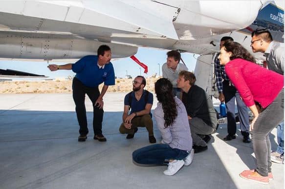 Interns look under an F-15 with a NASA engineer.