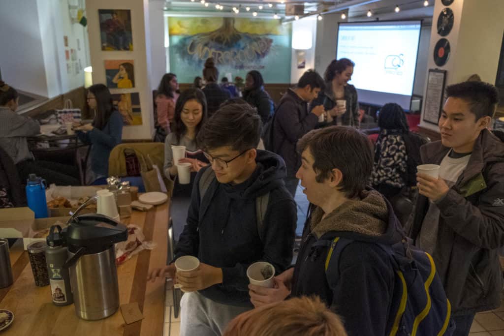 Many students socialize in the open space of the coffeehouse while drinking coffee.