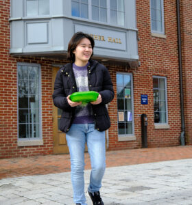 Huang Xinlei '26 leaves Mather Hall with one of Trinity's new reusable takeout containers. (Photo by Helder Mira)