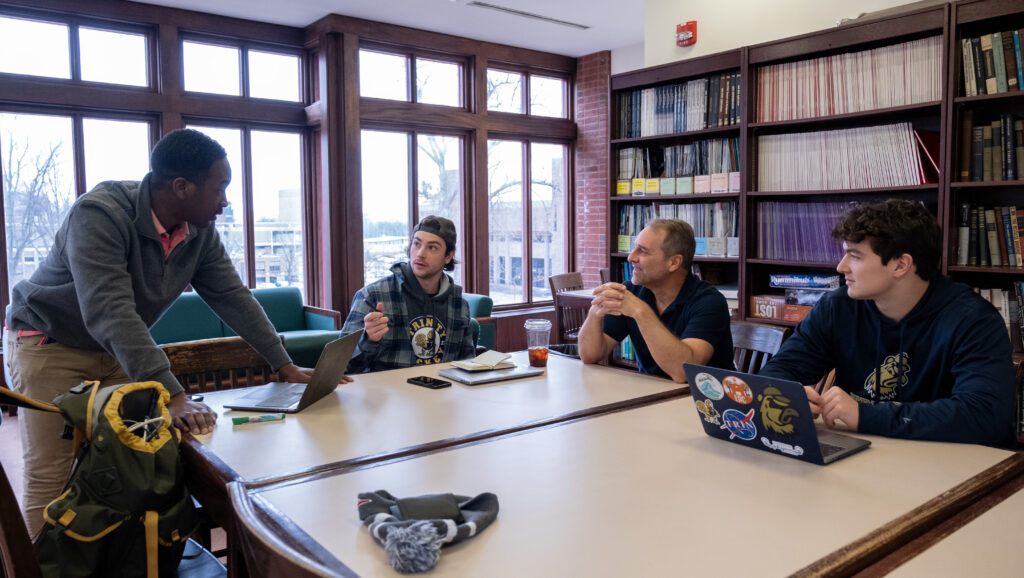 Maalik McPherson ’23 (left) speaks with Eric Sinson ’23, Professor of Engineering John Mertens, and Kevin Clark ’23.