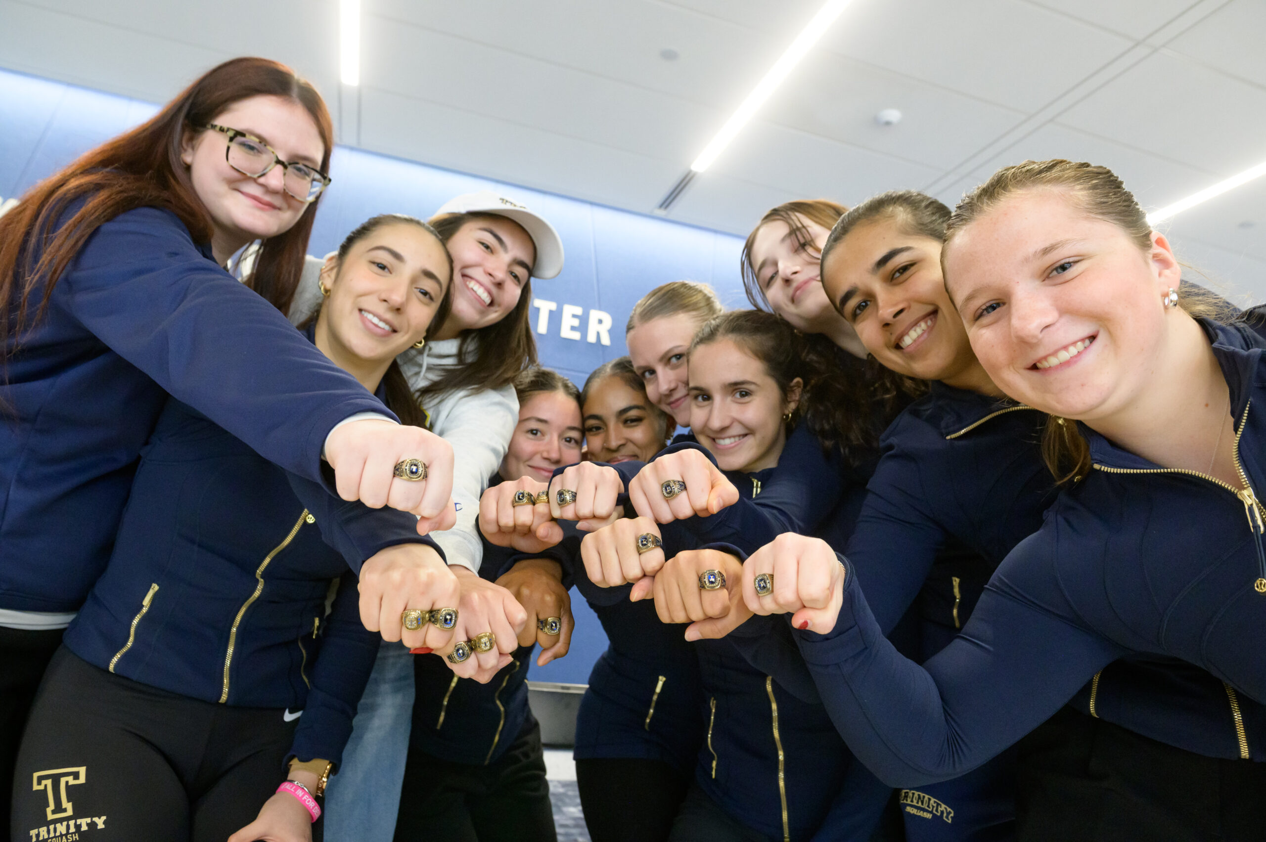 Women's squash players showing off their rings