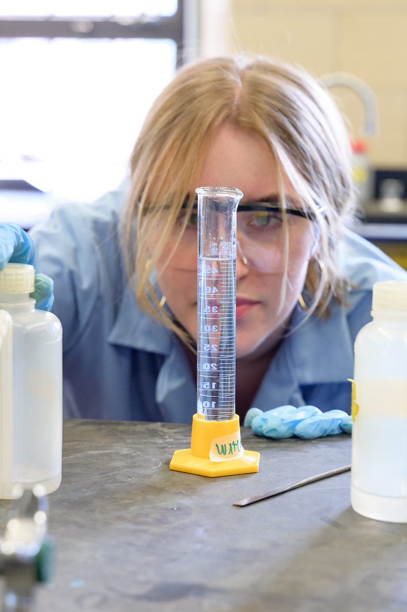 A student looks at a graduated cylinder