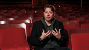 A student gestures with his hands while speaking in a theater